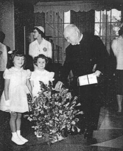 Photo of Cardinal Spellman receiving flowers for dedication of the shrine
